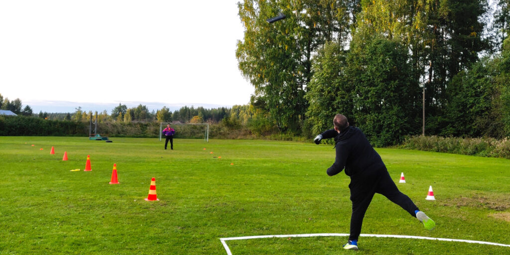 Mies heittää saapasta Kolman nurmikentällä